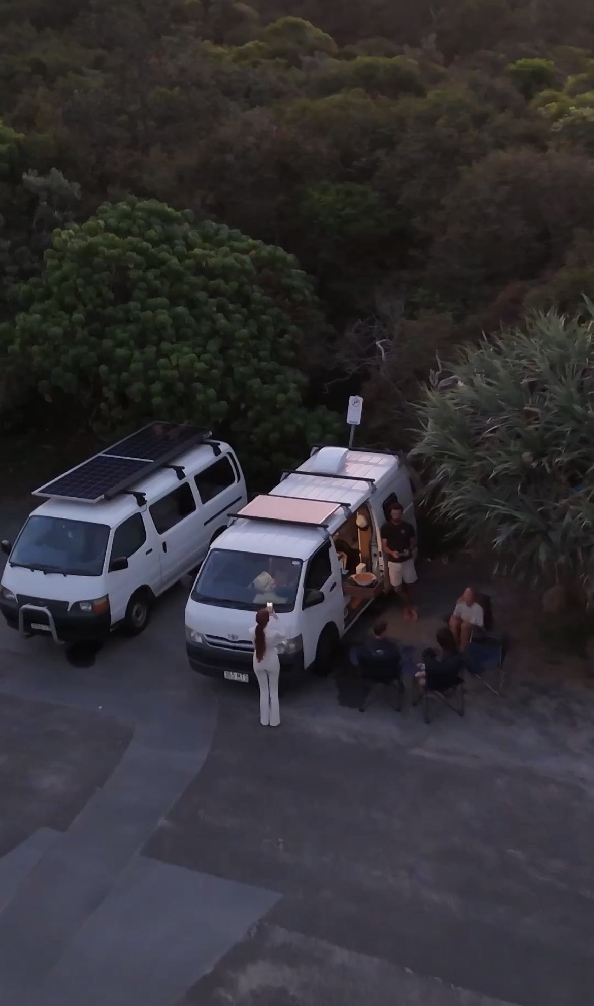 Travellers camped beside a van at dusk