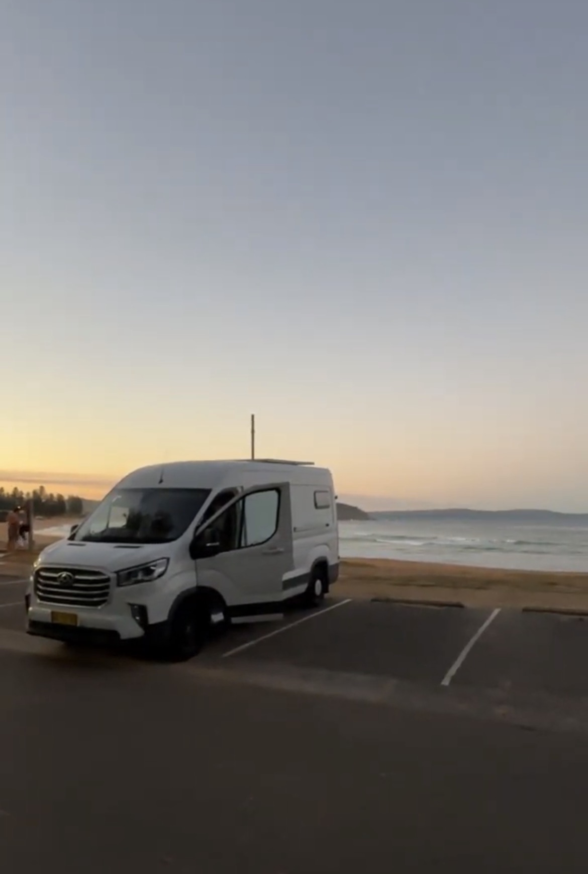 A campervan parked by the beach at dawn on the east coast